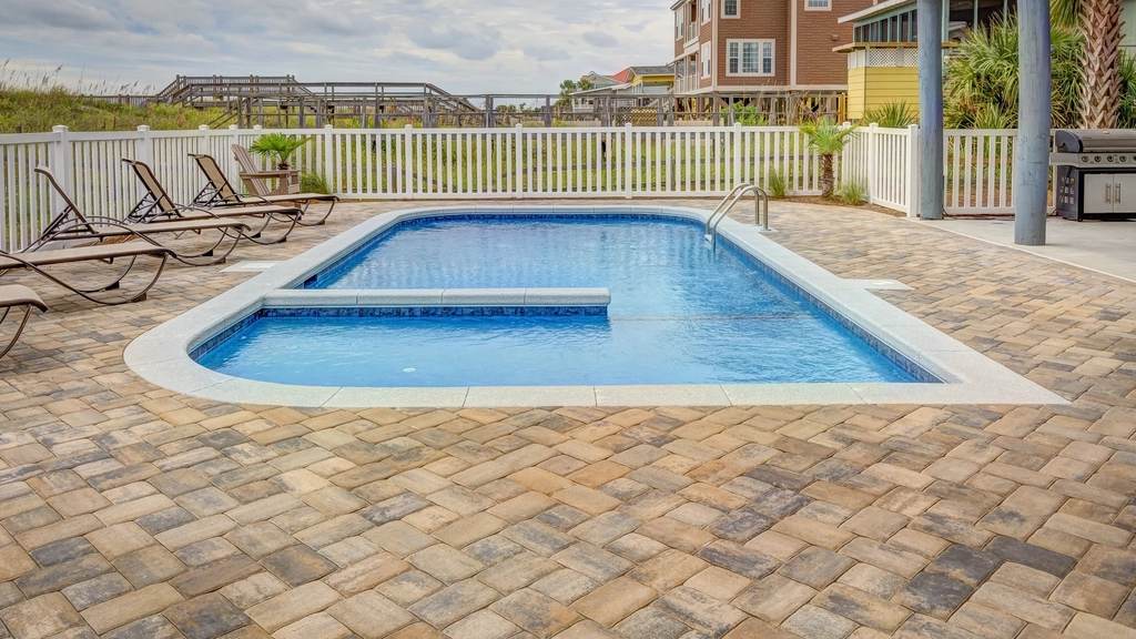 Swimming pool surrounded by a tan and gray paver pool deck